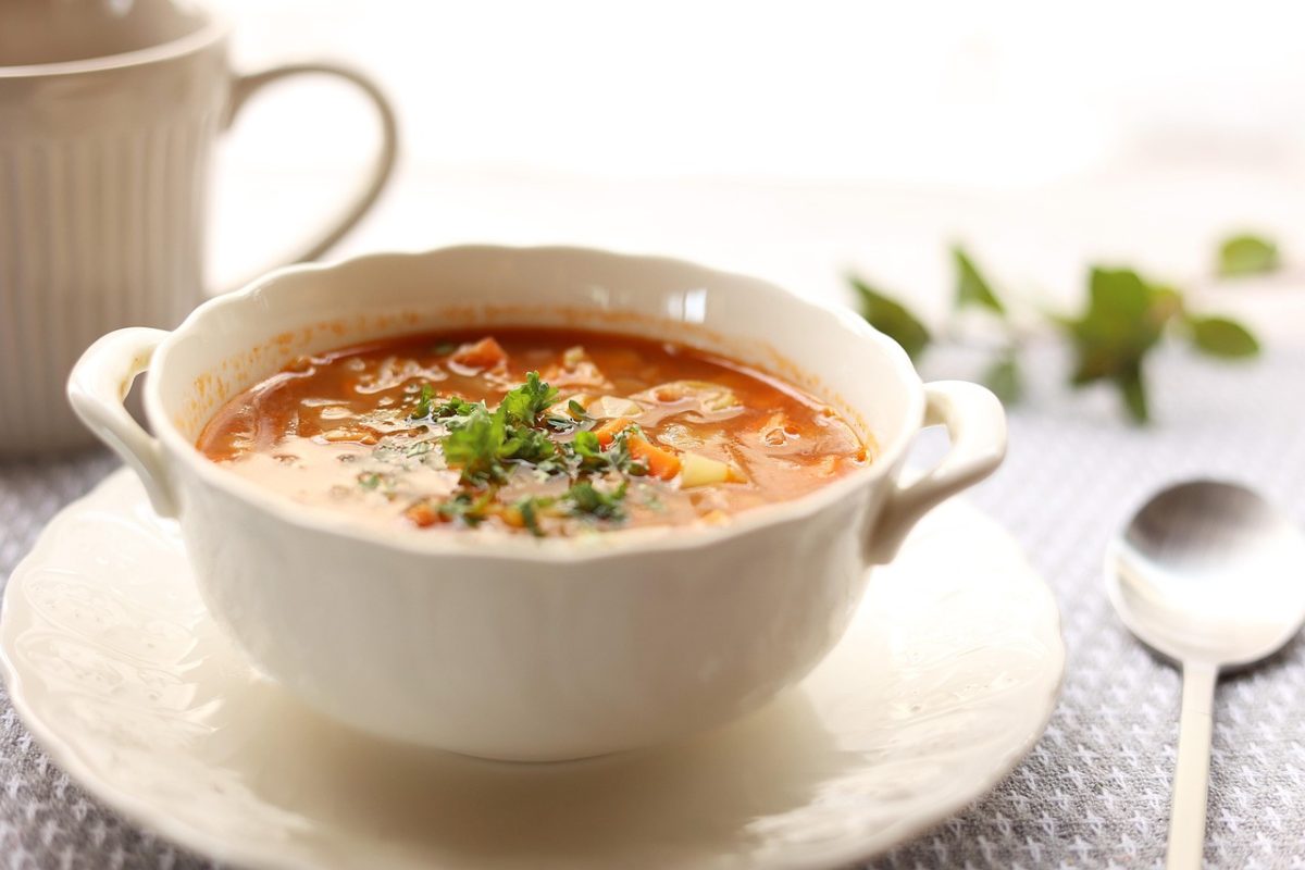 Sopa fitness de lentejas rojas con vegetales frescos en un plato blanco, receta saludable rica en proteínas ideal para deportistas – Essentials Workout.